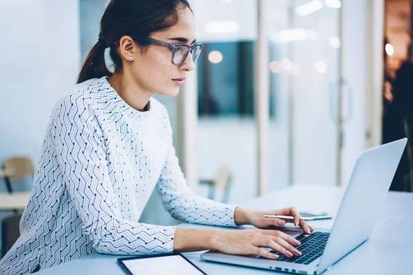 Professional female administrative manager of clinic typing on laptop computer information for web page content,skilled businesswoman reading documentation and keyboarding feedback on netbook