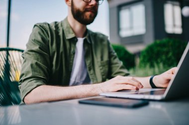 Yeni dizüstü bilgisayar, bilgi aramak ve serbest netbook açık havada üzerinde klavye üzerinde çalışan erkek programcı yazarak Sokak kafede oturan genç beyaz hipster biri kırpılmış görüntü