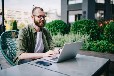 Genç hippi çocuk çevirmen tarafından internet, dil öğrenme en sevdiğim kafede yeni dizüstü bilgisayar kullanarak izlerken webinar online yolu ile modern aygıt dostum ve sosyal ağlarda takipçileri ile iletişim kurar.