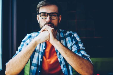 Kameraya bakarak sağlamak gözleri koruma için optik gözlük sakallı genç adam yarım uzunluk portre. Yakışıklı erkek blogger ciddi bir yüz ile şık casual gömlek giymiş