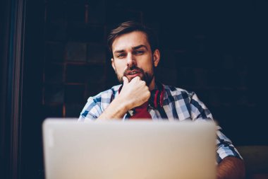 Serbest üzerinde çalışma ve dizüstü bilgisayarda kablosuz 4 g internet bağlantısı kullanarak yakışıklı sakallı hippi adam portresi. Netbook okurken kameraya bakarak boyun kulaklık ile genç adam