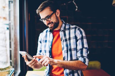 Neşeli sakallı blogger smartphone aygıt üzerindeki sosyal ağlar komik yorum okuma için 4 g bağlıyken gülüyor Internet. Modern cep üzerinde arkadaşlarınızla sohbet online olumlu hippi herif