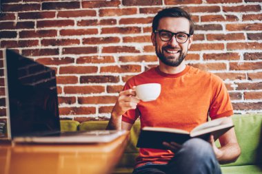 Gözlük kamera ise zevk kahve ve ilginç bir kitap gülüyorsun vizyon düzeltme sakallı genç adam portresi. Başarılı öğrenci ders kitabı lezzetli içecek holding eller ile