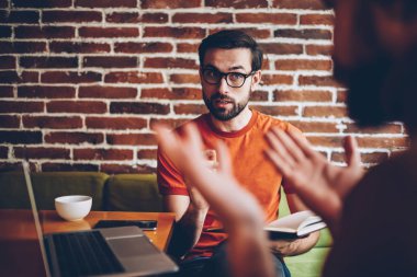 Ciddi optik gözlük alan coworking içinde toplantı sırasında arkadaşıyla tartışmaya genç adam sakallı. Birlikte laptop oturan ortak proje üzerinde meslektaşı ile strateji tartışmaya öğrenci