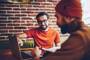 Dizüstü bilgisayarda işaret ve öğrenci için görev açıklayan profesyonel erkek grafik tasarımcı. İki hister yaratıcı genç adam, modern bilgisayar ortak proje üzerinde birlikte bağlı 4 g için Internet