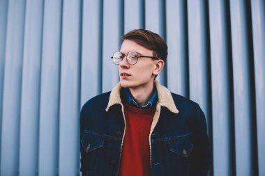 Uzak seyir vizyon düzeltme için şık gözlük yakışıklı hipster adam durulması. Düşünceli genç adam şık denim ceket ayakta açık havada kentsel ortamda giymiş. Düşünceli genç