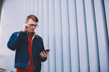 Yorum takipçileri blog Smartphone ile 4 g internet bağlantısı okuma sağlamak gözleri koruma için optik gözlük dalgın hipster adam. Genç adam web sitesinde cep video izlerken