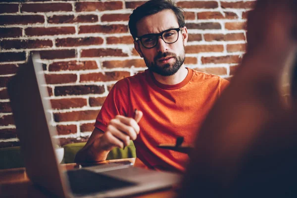 Hombre Joven Barbudo Escéptico Gafas Ópticas Mirando Dispositivo Computadora Portátil — Foto de Stock