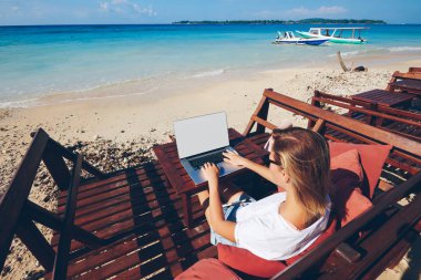 Sahte uzaktan güneşli okyanus kıyısında, vakit Asi tatil sırasında mesafe iş işkadını çalışma ekranı olan dizüstü bilgisayarda klavye yetenekli kadın bin yıllık serbest meslek