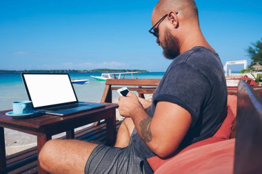 Modern teknoloji ve 4 g uzaktan okyanus plaj yaz aylarında çalışma internet, bin yıllık erkek blogger kontrol bildirim Smartphone cep telefonu ile güncelleştirmek journe onun web sayfa içeriği kullanan genç adam