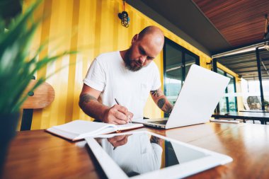 Ciddi bin yıllık erkek öğrenci dizüstü bilgisayar ve wifi college Kampüsü, notlar üzerinde serbest çalışma makale yayın için yetenekli erkek blogger kullanarak ödev Not Defteri'nde yazma