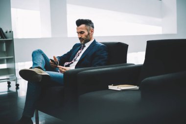 Dalgın emin işadamı bildirim koltukta oturan smartphone üzerinde okuma formal giyim giymiş. Orta yaşlı ofis çalışanı ile 4 g telefonu SMS mesaj gönderme konsantre Internet