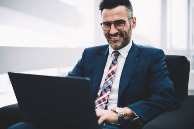Yarım uzunluk portresi başarılı iş adamı orta yaşlı muhasebesi raporu, dizüstü bilgisayar üzerinde çalışan kablosuz 4 g için bağlıyken kameraya gülümseyen Internet. Posta kontrol müreffeh gurur ceo