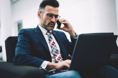 Olgun işadamı formal giyim laptop yolu ile 4 g enterne bağlantı Yöneticisi için smartphone üzerinde arama ve bankacılık bilgi telefon görüşmesi sırasında analiz sırasında veritabanı denetimi yoğunlaştı