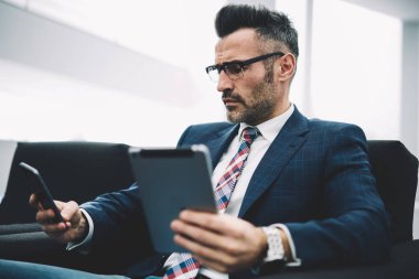 Modern Dokunmatik ped cihaz üzerinde hesap bankacılık profili güncelleştirilirken Smartphone cep telefonu ile gelen sms mesajý okuma formal giyim emin girişimci. Bluetooth ile medya paylaşımı gurur CEO'su Olgun