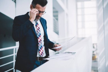 Dalgın emin icra müdürü kurumsal şirkette çalışan mali rapor okuma takım elbise giymiş. Olgun girişimci formal giyim bilgi veriyle metin belgeleri kontrol yoğunlaştı