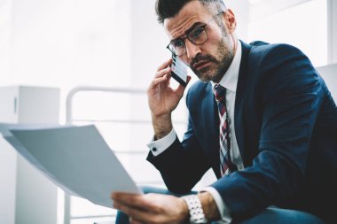 Ofiste çalışan Smartphone için işlecini çağırmak ellerinde mali metin raporlarla emin başarılı iş adamı. Gurur CEO'su 50 yaşında belgeler üzerinde telefon bankacılığı ile deneyimli