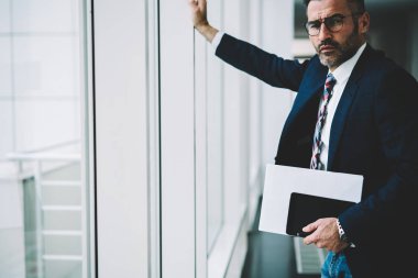 Kendine güvenen başarılı işadamı modern tablet aygıtı elinde tutan ve kameraya bakarak 50 yaşında yarım uzunluk portre. Finans şirketinin ciddi olgun sahibi formal giyim giyinmiş