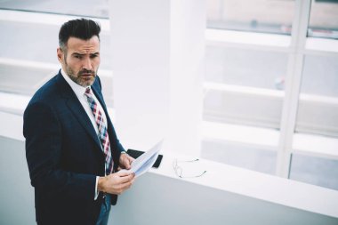 Üstten görünüm muhasebe raporları elinde tutan formal giyim giymiş başarılı emin girişimci 50 yaşında. Ciddi olgun gurur CEO'su kağıt belgeleri bankacılığı ile portresi