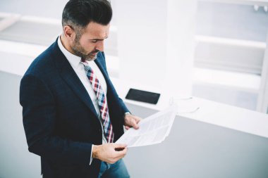 Üstten görünüm dalgın olgun girişimci finansal raporlar ile bilgi veri okuma formal giyim giymiş. Kapalı duran konsantre işadamı 50 yaşında muhasebe metni denetlemeyi makaleler