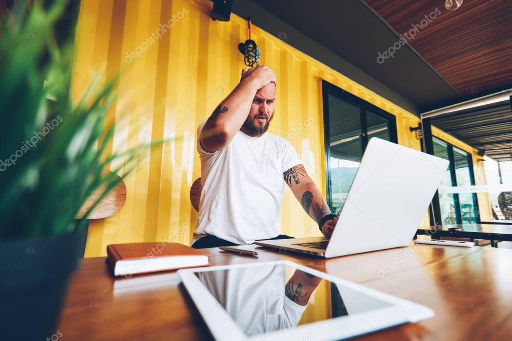 Worried caucasian male shocked with getting bill on mail checking banking balance online via laptop computer, sad male freelancer disappointed about failure with project and bad wifi connection