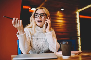 Genç kadın yardım hattı destek operatörü, yetenekli erkek café Interio oturan cep telefonu konuşma sırasında fikir açıklayan sırasında el hareketi ile telefon danışmanlık sırasında problem çözme