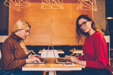 Ciddi meslektaşı, serbest web developmen üzerinde konsantre kafe iç üzerinde çalışan genç kadın ile dizüstü bilgisayar üzerinden sınavlarına hazırlanıyor kamera bakıyor zeki kız öğrencinin portresi