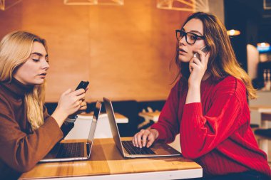 Modern teknoloji gerçek iletişim, meşgul kadın meslektaşları sohbet ve çalışma serbest dizüstü bilgisayar üzerinden arama için smartphone kullanarak görmezden kullanıp çalışmayı ciddi kadın konsantre