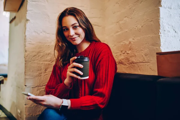 积极的十几岁女学生的肖像拿着咖啡杯看着相机 微笑的时髦女孩休息在 Coworking 空间持有智能手机连接到 Wifi 博客和网络 — 图库照片