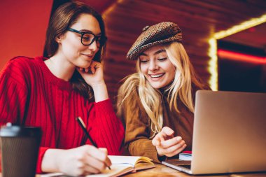 Birlikte yaratıcı tartışırken kafe Ardiles öğrenirken eğlenmek genç kız öğrencilerin ödev görev için mutlu hippi kız memnun proje üzerinde işbirliği ile verimli çalışma planı 