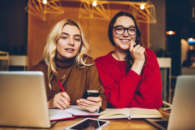 Ortak ev ödevi projede birlikte genç hippi kız vasıl yazıhane coworking içinde okul sırası oturan sınavlarına hazırlanması üzerinde işbirliği teknolojisini kullanarak çalışan zeki kız öğrenci portresi