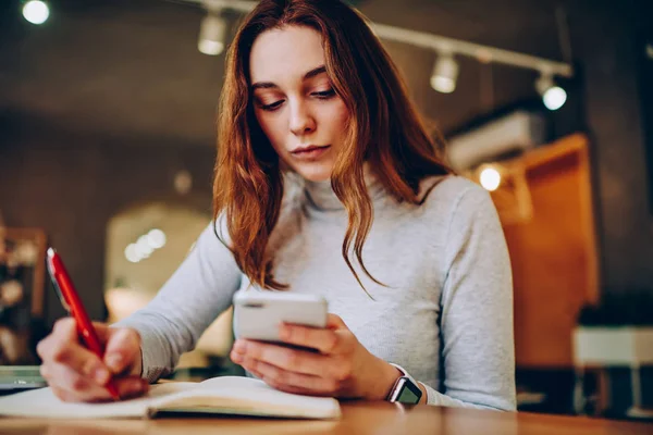 Donna Concentrata Notando Informazioni Smartphone Blocco Note Che Lavorano Remoto — Foto Stock