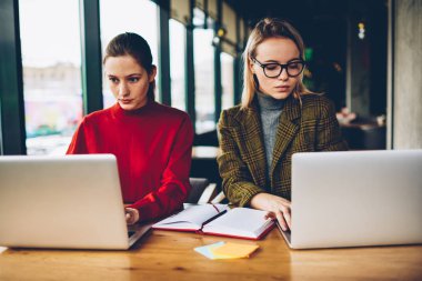Dizüstü bilgisayarda kablosuz 4 g için bağlı çalışan kadın grafik tasarımcıları konsantre Internet üzerinde serbest coworking. Dalgın iki akıllı öğrenciler netbook'lar üzerinde web sitelerinde bilgi arama