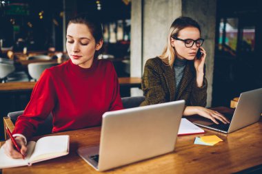 İki yetenekli grafik tasarımcıları uzaktan modern netbooks çalışma coworking kablosuz internet bağlı. Sarışın öğrenci smartphone metin içinde not etmek--dan website belirterek meslektaşım süre: çağrı