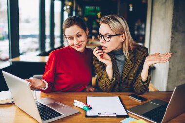 İki şüpheci yetenekli öğrenciler dizüstü bilgisayarda internet sitesinde tasarım tutorial online izlerken bilgi analiz ve tartışmak için kablosuz 4 g bağlı oturma alanı coworking internet