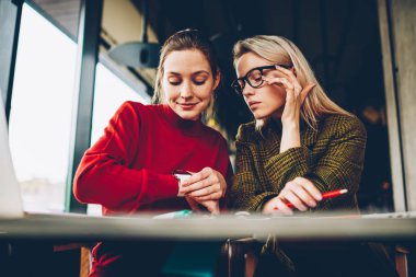 Eğitim zaman alan coworking içinde düzenlemek için düşünceli öğrenciler modern smartwatch göstermek vasıl arıyorum. Hippi kız kafe iç dostu toplantı sırasında kol saati kontrol