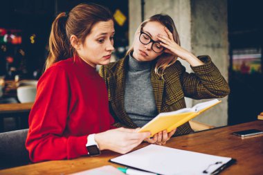 Karışık yetenekli öğrenciler ders kitabı bilgi alan coworking içinde sınava hazırlık sırasında merak. Eğitim materyali birlikte edebiyat kitap okuyan analiz sinirli hipster kızlar