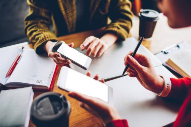 Modern smartphone aygıt boş ekran alanı ile tutarak ve paylaşımı kadınların elleri görüntüsünü bluetooth bağlantısı ile multimedya kırpılmış. Öğrenciler okul sırası vasıl oturan dijital telefon app yükleme