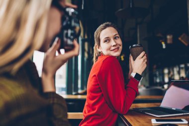 Lezzetli kafein içecek poz ve odaklanan ve coworking boş zamanlarında vintage kamerada fotoğraf yapma yetenekli kadın Amatör süre gülümseyerek elinde olan neşeli kadın üzerinde seçici odak