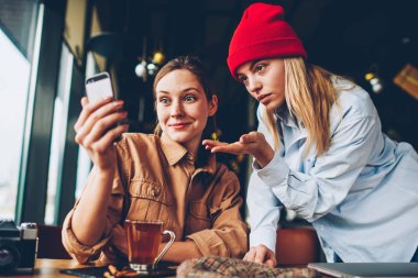 Hipster blogcular video web sitesi wich smartphone aygıt üzerinde online bağlı 4 g için izlerken üzerinde tartışırken merak internet kafede oturuyor. Şok öğrenciler canlı akışı mobil iletişim