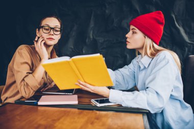 Ders kitabı okuma ve sınavları için birlikte uzay coworking hazırlanması iki genç yoğunlaşmıştır. Akıllı hipster kızlar Bilgi Üniversitesi'nde edebiyat kitabından öğrenme rahat kıyafet giymiş