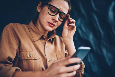 Hesap bankacılık hakkında smartphone aygıt üzerinde yaklaşan bildirim okuma Eyewear endişeli genç kadın. Dikkatle üstünde hareket eden telefon yolu ile 4 g uygulama yükleme konsantre hipster öğrenci internet