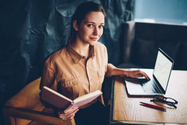Yarım dijital bilgisayar seminerde hazırlama büyüleyici yetenekli öğrenci portresi alan coworking içinde kablosuz internet bağlı. El kameraya bakarak ders kitabı ile çekici hippi kız