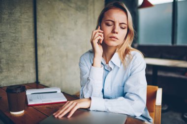 Ciddi hipster öğrenci kafede otururken smartphone aygıtında için işlecini çağırmak. Dalgın genç kadın dikkatle dinleme sesli mesaj kafede oturan telefonu operatörünüzden