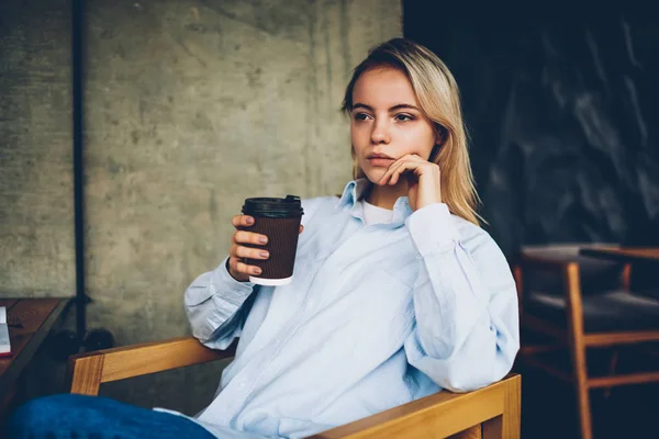 思いやりのある若い女性金髪ストレートを見ながら行く居心地の良いカフェテリアで休憩においしいコーヒーを保持している アイデアを熟考の手でカフェイン飲料で瞑想的な内気な少女 — ストック写真