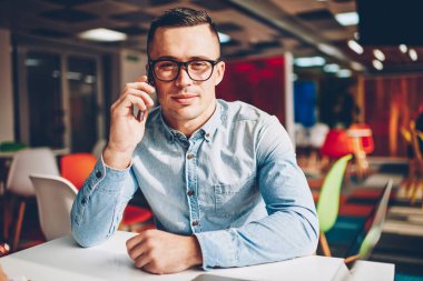 İş, hizmet operatör bankacılık ile telefon görüşmesi sırasında kameraya bakarak Eyewear genç işadamı telefon görüşmeleri yapma telefon tarifeler ile portre profesyonel erkek Yöneticisi memnun