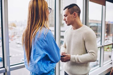 Kadın ve erkek meslektaşlarım, fikir paylaşımı çalışma projesinin yapımı çözümler iletişim sırasında dostça sohbet cowokers ayakta modern iç ofis penceresinde yakınındaki kırmak