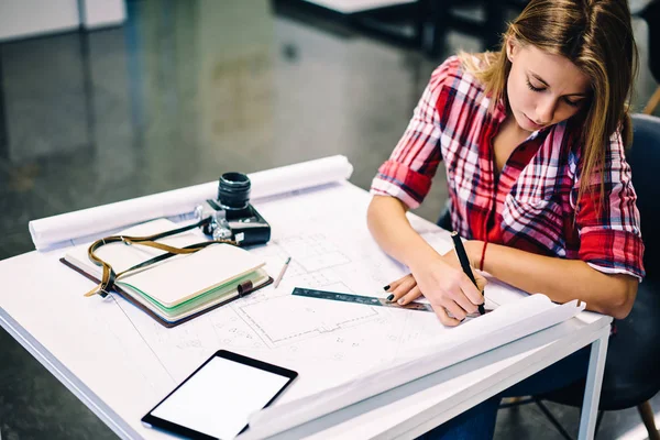 Professional female architect drawing blueprint of construction using stationery and equipment at desktop, creative girl studying design courses in college making drafting sketches for homework