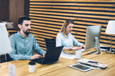 Dalgın erkek ve kadın ofis çalışanları metni klavye kullanarak Internet Web siteleri hakkında bilgi aramak için modern bilgisayarlara bağlı. Grafik tasarımlarıyla ofis iç dijital dizüstü bilgisayarlar çalışma