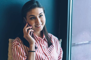 Portre resim güzel neşeli kadın Blogger cep üzerinden mobil konuşmayı şık gömlek giymiş. Sevimli gülümseyen hippi kız kapalı otururken modern smartphone konuşuyor